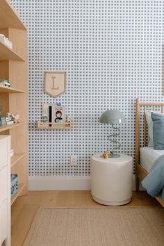 a bedroom with blue and white wallpaper, wooden shelves and a small child's bed