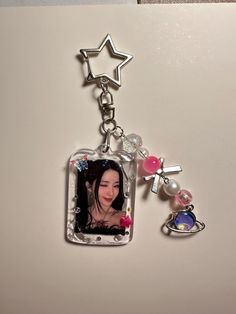 a keychain with an image of a woman and two charms attached to it