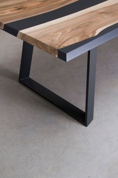 a wooden table sitting on top of a cement floor next to a black metal frame