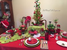 a table set for christmas dinner with red and green plates, silverware and decorations