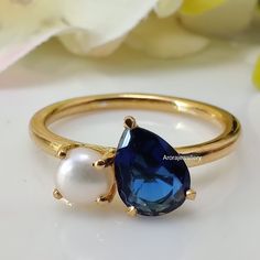 a gold ring with a blue stone and a white pearl