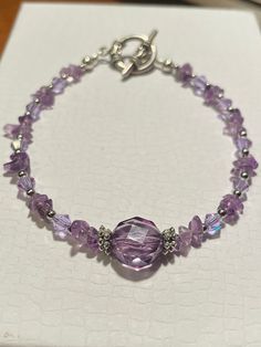 7 and a 1/2-inch-long beaded bracelet. February birthstone amethyst chip natural beads, light purple crystal beads, and silver-plated spacers. Closes with a silver tone antiqued toggle clasp. It has one bigger purple crystal bead in the middle. Silver Amethyst Beaded Bracelets, Silver Crystal Bracelet With Amethyst Beads, Adjustable Purple Sterling Silver Crystal Bracelet, Purple Sterling Silver Beaded Bracelets With Round Beads, Adjustable Purple Sterling Silver Beaded Bracelets, Adjustable Sterling Silver Purple Beaded Bracelets, Silver Amethyst Beaded Bracelets With Natural Stones, Silver Amethyst Crystal Bracelet With Gemstone Beads, Silver Amethyst Beaded Bracelets With Faceted Beads