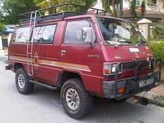 a red van is parked on the side of the road in front of a house