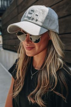 a woman wearing sunglasses and a hat with the word phi on it, standing in front of a building