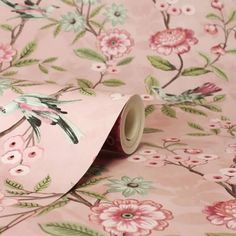 a pink flowered wallpaper with green leaves and flowers on the background is rolled up