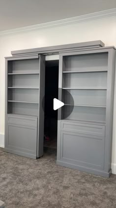 an empty room with two gray bookshelves and carpeted flooring in it