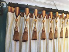 curtains with tassels hanging on them in front of a curtain rod and window