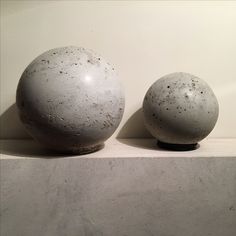 two white balls sitting on top of a counter next to each other in front of a wall