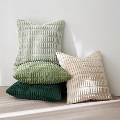 three pillows stacked on top of each other in front of a white wall and floor