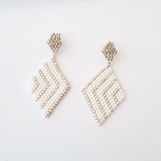 Rhombus white woven earrings. Here are some delicate stud earrings made with Miyuki beads and completely hand-woven by me. Delicate Rhombus shaped earrings, with Miyuki beads in white and silver colors. Refined and very light to wear. The base that holds the earring is in stainless steel. Features of the earrings are: Length: 4.5cm Width: 2.3cm Here you can see other designs of white, gold and silver earrings: https://www.etsy.com/shop/AQBijouterie?ref=seller-platform-mcnav&section_id=34429251 Elegant Geometric White Jewelry, Elegant White Geometric Jewelry, Handmade White Beaded Rectangular Earrings, Handmade White Rectangular Beaded Earrings, Gold And Silver Earrings, Woven Earrings, Rhombus Shape, Beaded Earrings Patterns, Miyuki Beads