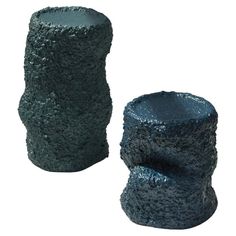 two black vases sitting next to each other on a white surface, one is made out of concrete