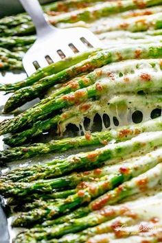 asparagus covered in melted cheese and parmesan sauce with a fork on the side