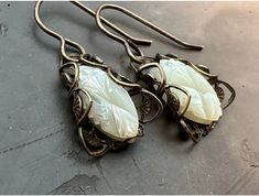 "These mother of pearl carved gorgeous stones have been UPCYCLED into earrings!! Antique brass filigrees bring these beautiful deco stones back into circulation. The stones were uncovered from old warehouse jewelers stock. MINT condition and never designed with. The filigrees are Miriam Haskell vintage old stock findings. What a pairing! 1 1/4\" in length. Stone size: 3/4\" If you buy more than 5 items in the store, shipping is FREE." White Carved Earrings For Gift, White Victorian Handmade Earrings, Handmade White Victorian Earrings, Handmade Victorian White Earrings, Ornate White Carved Jewelry, White Victorian Jewelry With Carved Details, Victorian White Carved Jewelry, White Victorian Carved Jewelry, Antique White Jewelry With Matching Earrings