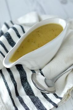 a white bowl filled with soup sitting on top of a striped cloth next to a spoon