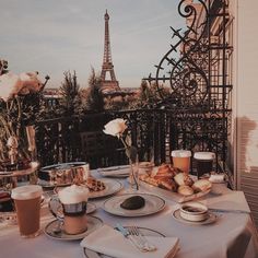 a table with food and drinks on it in front of the eiffel tower