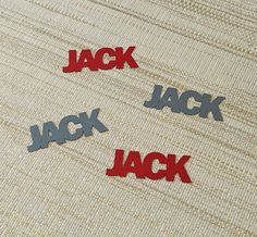 three red and black letters that spell out the word jack on a beige fabric background