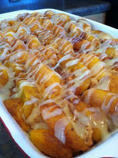 a casserole dish filled with cinnamon rolls covered in icing