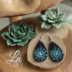 a pair of earrings sitting on top of a wooden table next to a succulent plant