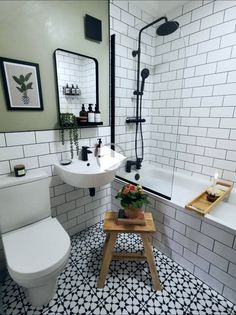 a white toilet sitting next to a bath tub in a bathroom with black and white tiles