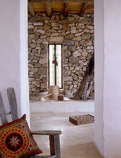 a stone building with a wooden bench in front of it and an open door leading to another room