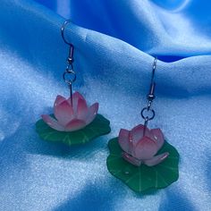 Introducing our Lotus Flower Earrings - a symbol of purity and beauty in a charming accessory. These earrings feature delicate lotus flower charms that add a touch of elegance to your style. Perfect for everyday wear or special occasions. Approximate Dimensions (Excluding Hooks): Height: 5cm, Width: 4cm Material: Resin Care instructions: For best results, please keep these away from water, perfume and other chemicals. Store in a cool, dry place. Disclaimer: Our earring hooks are typically friendly on the skin, however they may not be suitable for hyper-sensitive and hyper-allergic skin. This includes our stainless steel and sterling silver earrings. Lily Pad Earrings, Afro Jewelry, Lotus Flower Jewelry, Cool Earrings, Flowers Earrings, Pretty Jewelry Necklaces, Lotus Earrings, Water Perfume, Earrings Clay