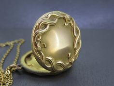 "Lovely antique locket set with an ornate design.  Opens and closes with a snap.  Nice and thick locket, well made. No frames/covers inside and some patina inside.  A little patina on the outside, some wear to the finish, and some very tiny dings.  Comes with a brand new 18\" gold plated stainless steel chain. All items added to your cart at Ribbons Edge will automatically combine shipping. To stay up to date with my newest offerings, follow me on IG @ RibbonsEdge" Antique Locket Necklace With Intricate Round Pendant, Antique Gold Filigree Locket Necklace For Formal Occasions, Antique Round Pendant Locket Necklace With Intricate Design, Antique Gold Engraved Locket Necklace Collectible, Vintage Locket Necklace With Intricate Design For Formal Occasions, Vintage Formal Locket Necklace With Intricate Design, Antique Gold Medallion Locket Necklace With Intricate Design, Antique Medallion Locket Necklace With Intricate Design, Vintage Medallion Locket Necklace With Intricate Design