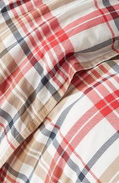 a red, white and blue checkered shirt laying on top of a bed sheet