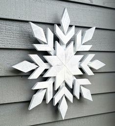 a white snowflake on the side of a gray house with wood slats