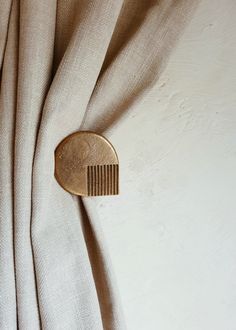 a gold hair comb on top of a beige curtain