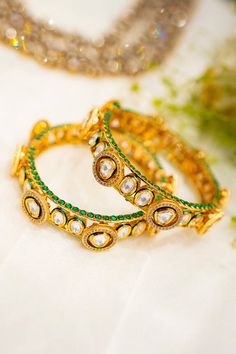 22k gold plated pacheli bangles with clear polki stone studded round patterns and emerald green stones. - Aza Fashions Bollywood Style Designer Gold Jewelry, Gold Meenakari Jewelry For Designer Wear, Gold Designer Jewelry For Diwali, Gold Jewelry For Designer Diwali Wear, Gold Jewelry For Designer Wear Diwali, Hand Set Yellow Gold Chandbali Bangle, Festival Jewelry With Gota Work For Designer Wear, Festive Jewelry With Gota Work, Festive Round Jewelry With Gota Work