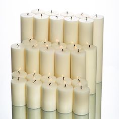 a stack of white candles sitting next to each other in front of a white background