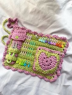 a crocheted pink and green purse on a white sheet with the words hello kitty written across it