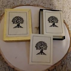 three framed pictures with trees on them sitting on top of a tree stump in front of a carpeted floor