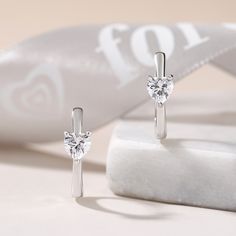 Sweet and sparkling, these simple hoop earrings relay your affection. Fashioned in fine sterling silver, these charming hoops are set with a shimmering heart cut stone, adding a hint of glimmer. A small heart design is set on the earring, lending it a clean and classical look.Carat Weight: 1.6 ctStone Size: 5*5 mmStone Type: Jeulia® StoneNumber of Stones: 2 Stone Color: Diamond WhiteStone Shape: HeartWeight: 2.9 gWidth: 5.1 mmHeight: 6.3 mmThickness: 3.7 mmMaterial: 925 SilverPlating Color: Silv Silver Huggie Earrings With Heart Charm For Anniversary, Elegant Silver Heart Huggie Earrings, Elegant Silver Huggie Heart Earrings, Elegant Silver Huggie Earrings With Heart Charm, Silver Elegant Huggie Earrings With Heart Charm, Elegant Sterling Silver Huggie Earrings With Heart Charm, Silver Hoop Earrings With Heart Charm For Anniversary, Elegant Small Hoop Earrings For Valentine's Day, White Gold Heart Huggie Earrings For Anniversary