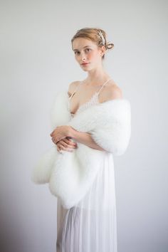 a woman wearing a white dress and fur stole