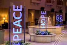 there is a sign that says peace and hope in front of a fountain with flowers