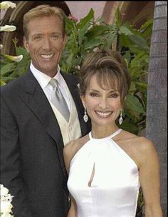 a man in a suit and woman in a white dress standing next to each other