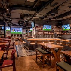 an empty sports bar with several televisions on the wall and tables in front of them