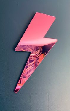 a pink lightning sign mounted to the side of a wall in front of a blue wall