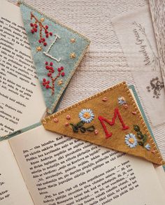 an open book with embroidered letters and flowers on it