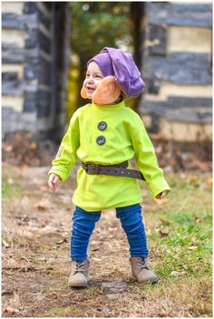 a small child wearing a green jacket and purple hat