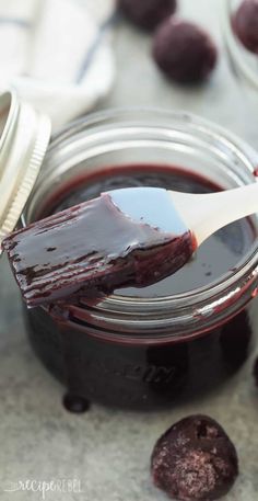 a spoon full of blueberry jam with chocolate cookies in the background