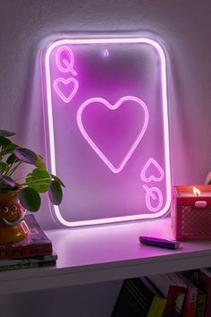 a neon sign with a heart in the middle on a shelf next to a potted plant