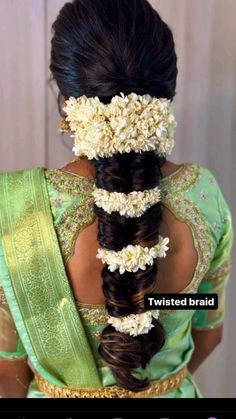 the back of a woman's head with flowers in her hair and two braids