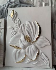 a white and gold flower is on the wall next to some other items that have been made out of paper