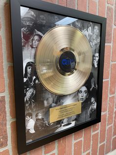 a gold record in a black frame on a brick wall