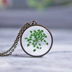 a glass pendant with a green plant on it