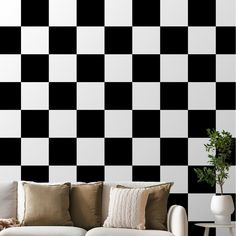 a black and white checkerboard wall in a living room with couches, table and potted plant