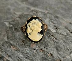 A gorgeous detailed cameo with a black background and cream relief set in detailed antiqued brass. Ring is antiqued brass with an adjustable, detailed band. Details: Ring measures 20mm x 15mm Ring band is adjustable, sizes 6 - 8-1/2 Ring is plated brass Lead & Nickel free Cameo is hard, matte resin Please allow for possible slight color differences due to different settings on different screens. Thank you for shopping Delicate Industry :) Antique Cameo Ring, Victorian Cameo Rings As Gift, Vintage Black Cameo Ring, Black Cameo Ring As Gift, Black Cameo Ring For Gift, Black Cameo, Gift Ideas For Mom, Jewelry Holiday, Unique Christmas Gift