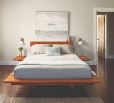 a large bed sitting on top of a wooden floor next to a painting above it